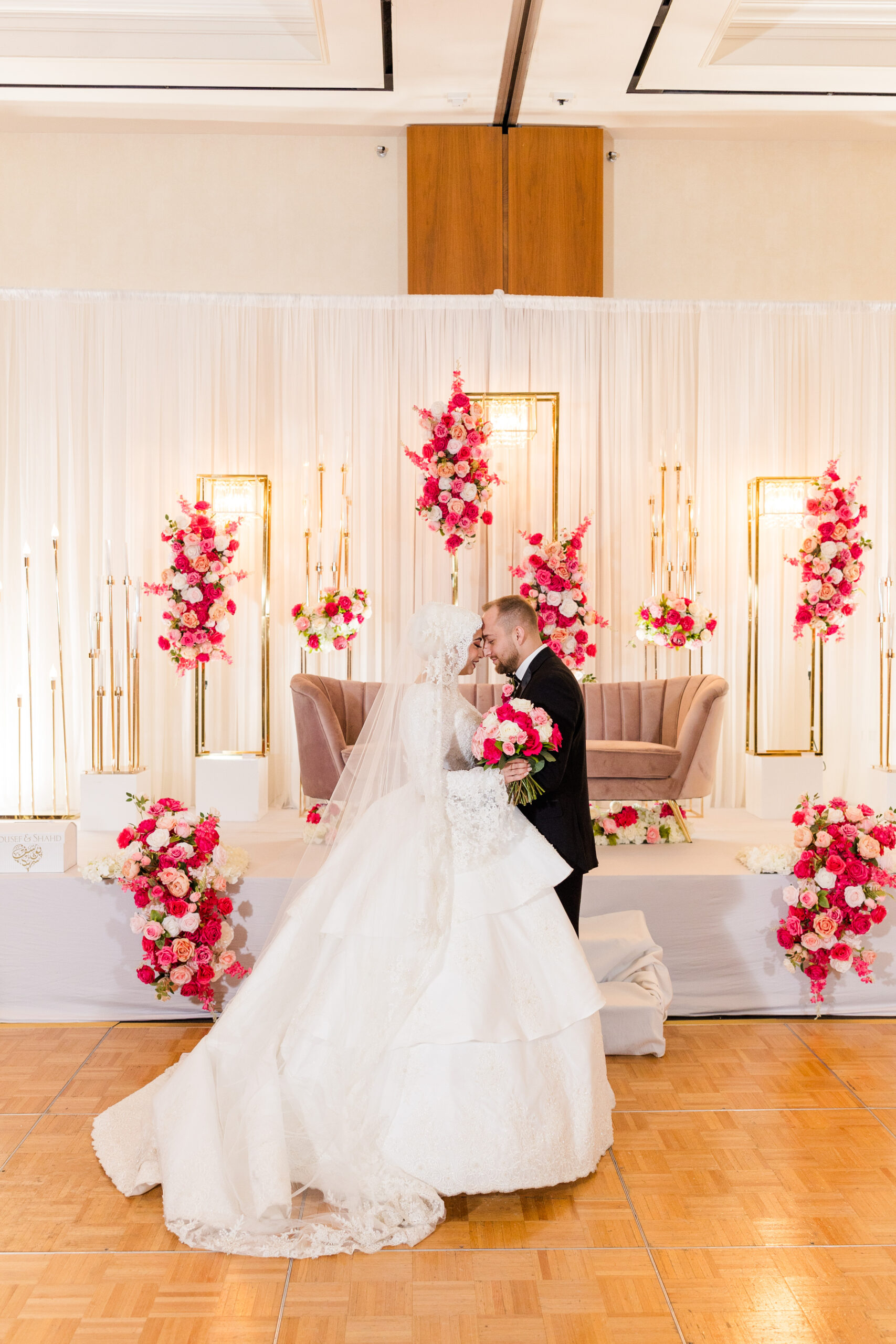 Bride and groom standing in front of wedding decorations at a ballroom reception.