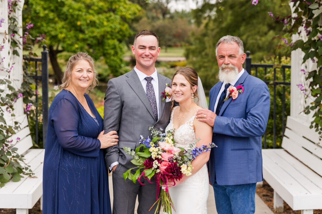 Bride and groom with parents taking wedding family photos outdoor in the spring